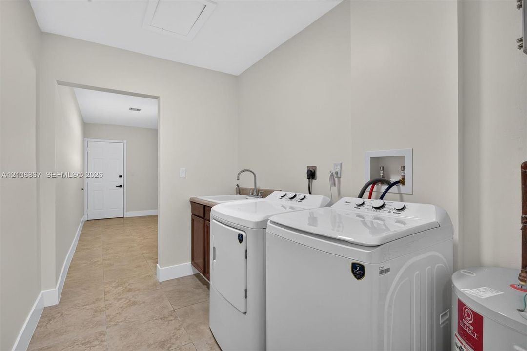 Laundry area featuring tile flooring, a built-in cabinet with a sink, and dedicated water and electrical hookups