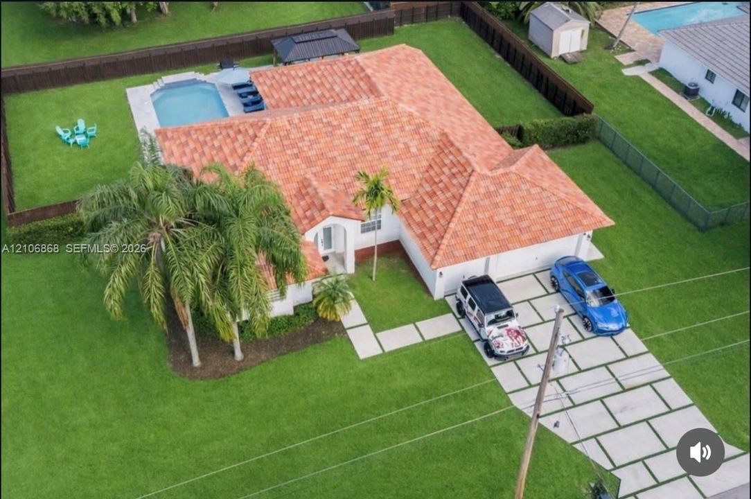 Tile roof residence featuring a concrete paver driveway, an in-ground swimming pool, a fully fenced backyard, and mature landscaping
