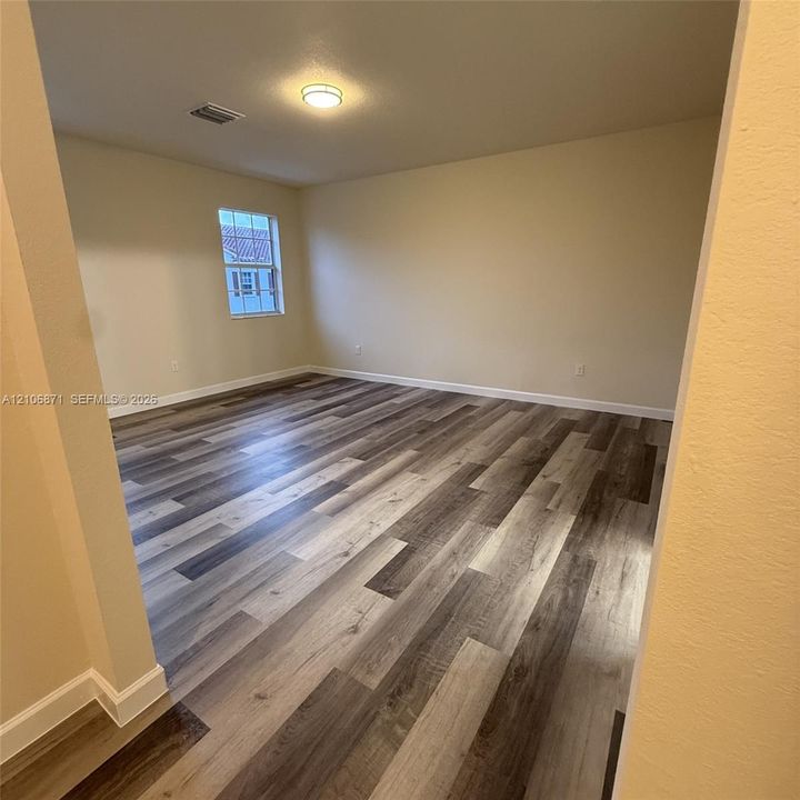 Interior room featuring wood-finish flooring, neutral wall paint, and a single-pane window with white trim