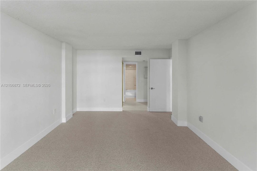 Neutral-toned carpeting, smooth-finish walls, and a solid-core interior door