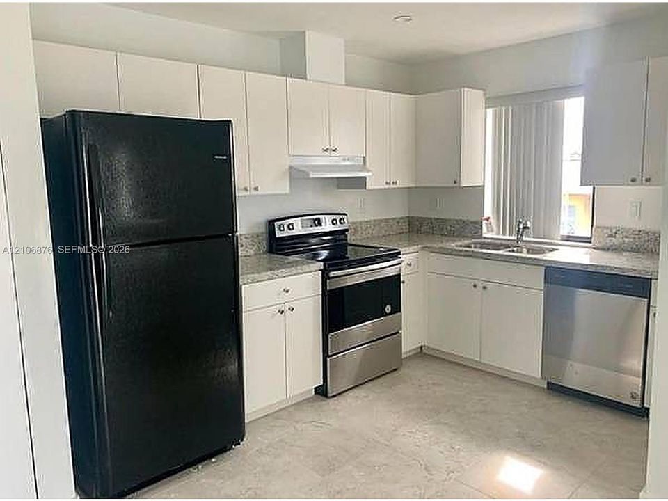 Kitchen featuring white cabinetry, stone-finish countertops, stainless steel appliances, and tile flooring