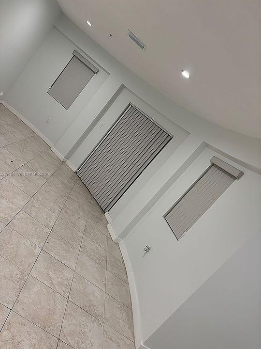 Neutral-toned tile flooring, recessed ceiling lighting, and vertical window blinds
