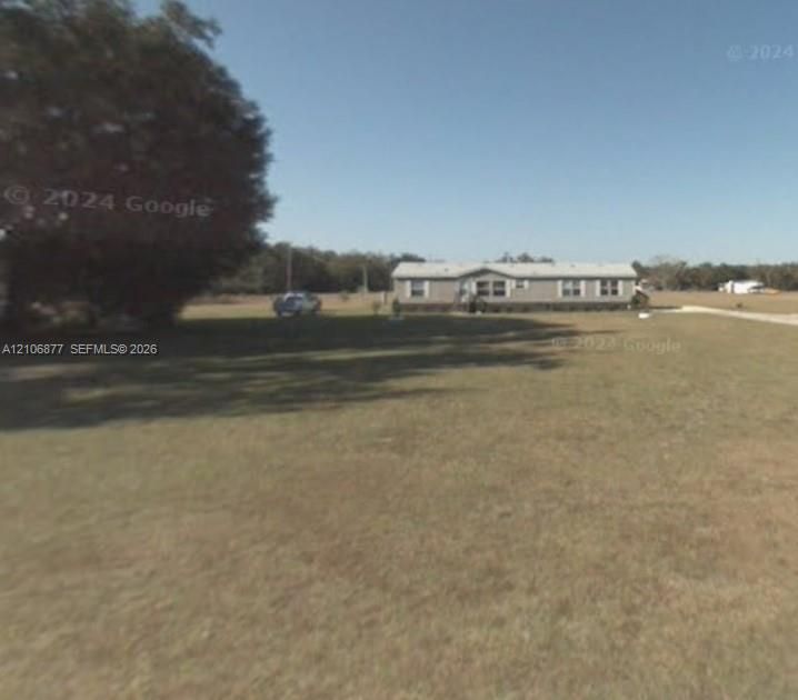 Expansive lot featuring mature trees and open green space surrounding a single-story residence