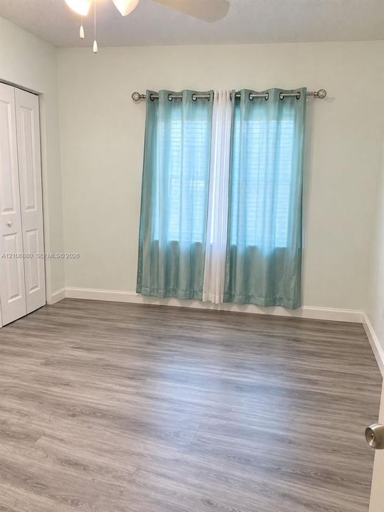 Wood-finish flooring, dual-panel closet doors, and a ceiling-mounted light fixture.