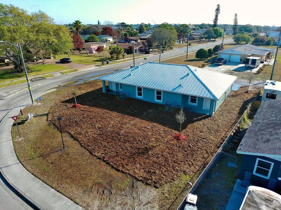 Corner lot property featuring a light blue exterior, metal roofing, and expansive grounds