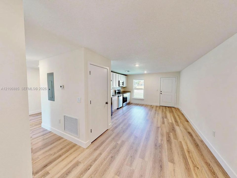 Open-concept interior featuring light-tone wood-finish flooring, recessed lighting, and kitchen cabinetry with integrated appliances