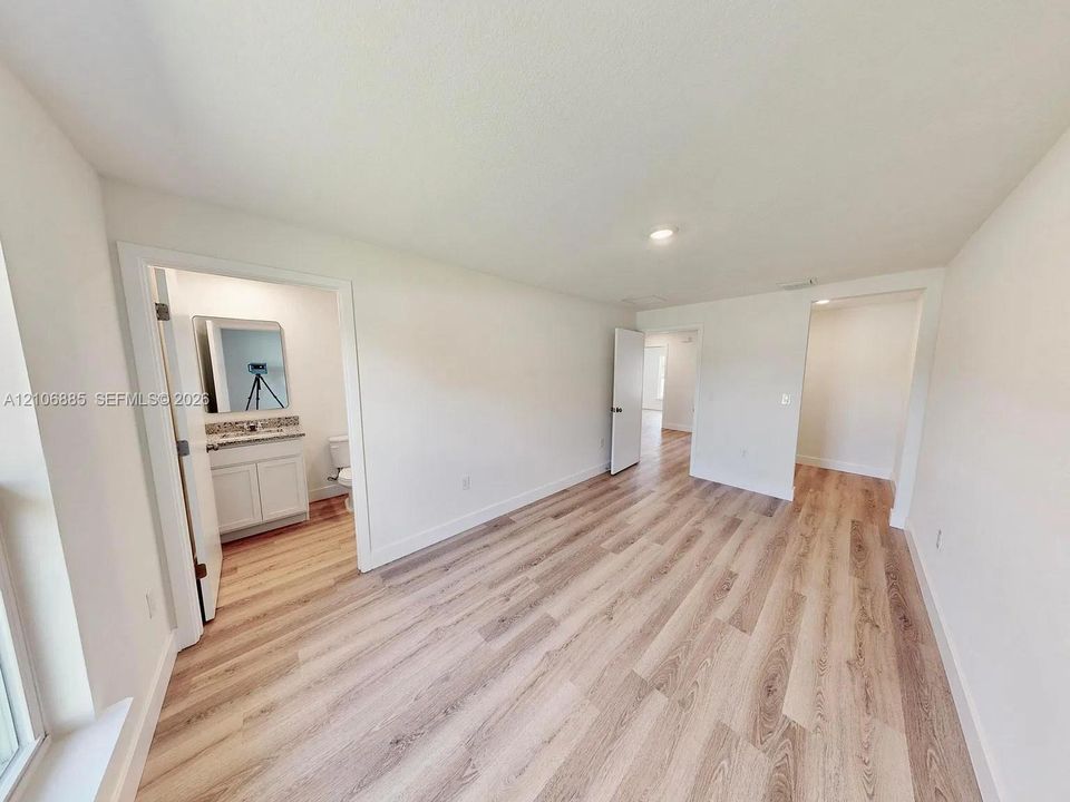 Wood-finish flooring, recessed lighting, and a bathroom vanity featuring stone-style surfacing and integrated cabinetry