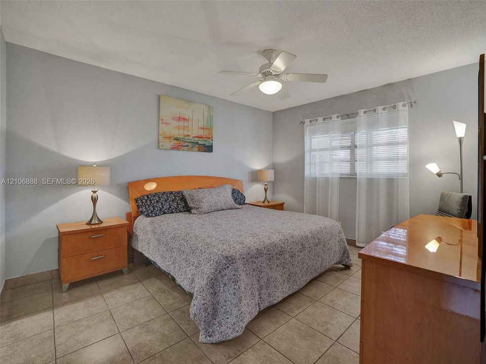 Neutral-tone interior featuring large-format ceramic tile flooring, a ceiling fan with integrated light fixture, and horizontal window blinds