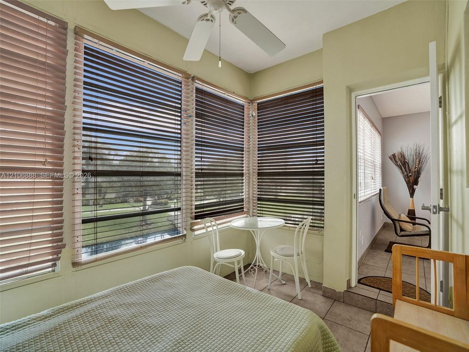 Sunroom featuring ceramic tile flooring, a multi-blade ceiling fan, and wrap-around windows with installed horizontal blinds