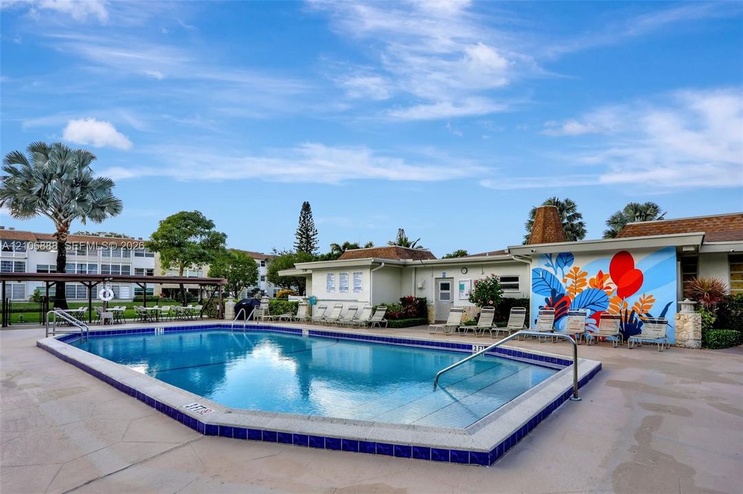In-ground swimming pool with tile trim, concrete deck, and built-in metal handrails