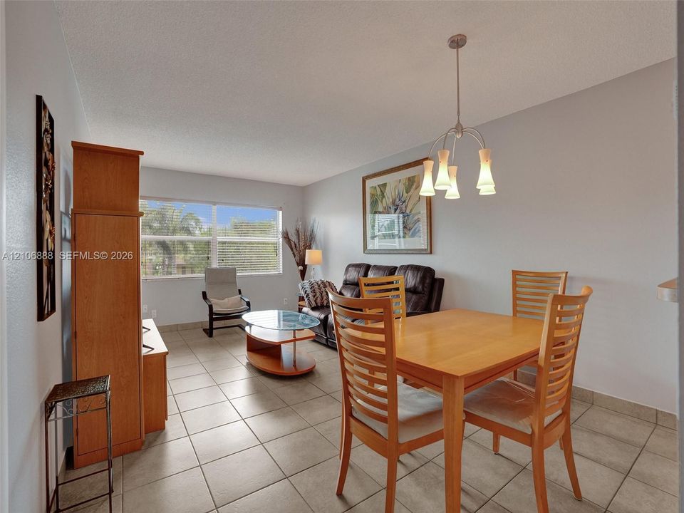 Neutral-toned ceramic tile flooring, multi-arm metal pendant lighting, and large window with horizontal blinds