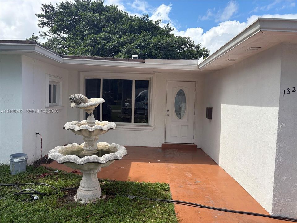 Stucco exterior featuring an entry patio, tiered stone fountain, and white front door with an oval glass insert