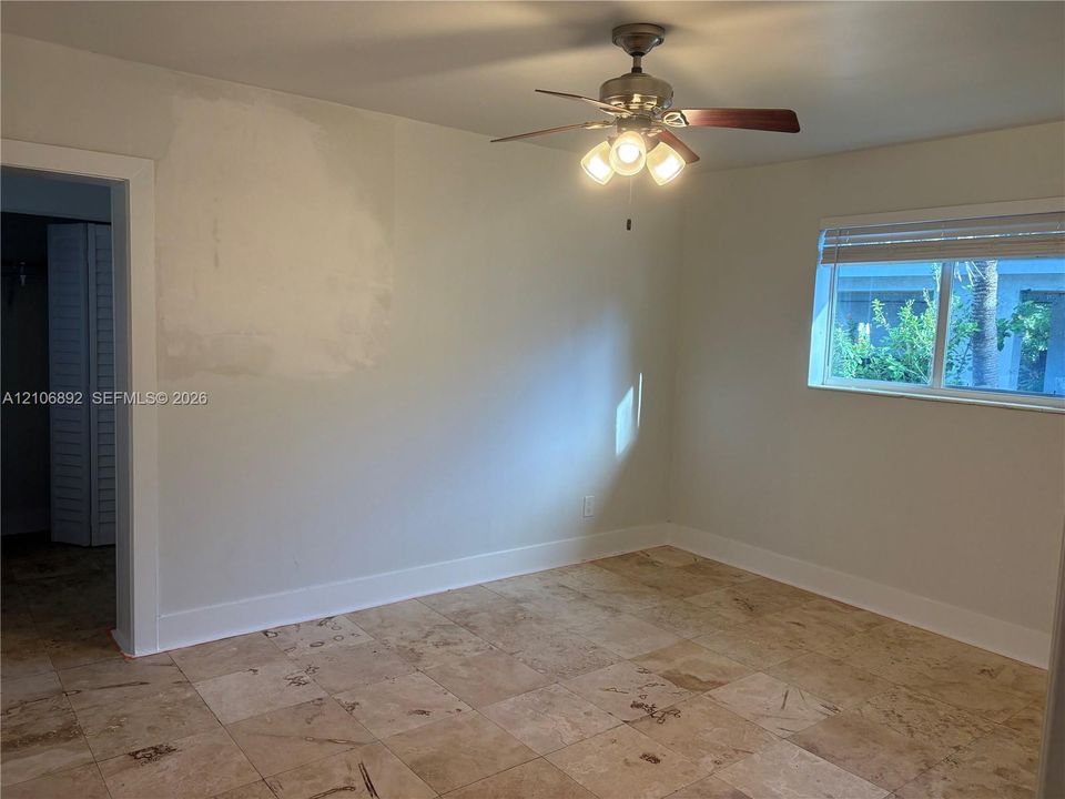 Room featuring large-format tile flooring, a multi-light ceiling fan with dark wood-finish blades, and a horizontal sliding window