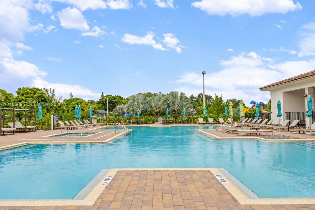 Swimming pool with integrated spa, surrounded by expansive paver decking and mature landscaping