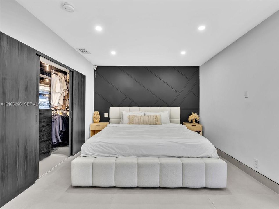 Interior room featuring a geometric paneled charcoal accent wall, recessed lighting, and large-format tile flooring