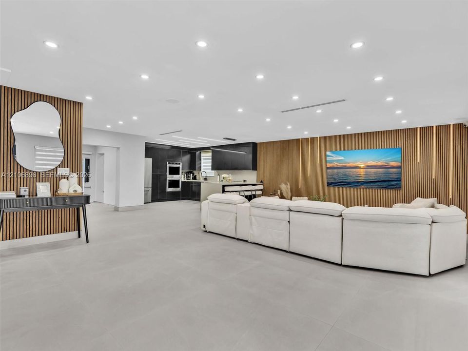Large open interior space featuring vertical wood-slat accent walls, recessed ceiling lighting, and neutral large-format tile flooring