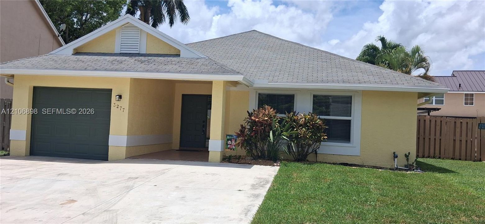 Stucco exterior residence featuring a covered entryway, attached garage, gabled roofline, and landscaped front yard