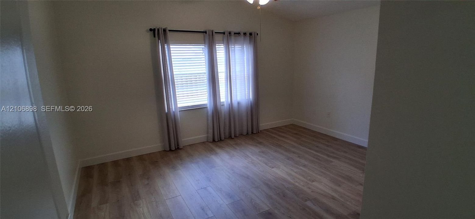 Interior space featuring wood-finish flooring, vaulted ceiling, and dual-pane window with horizontal blinds