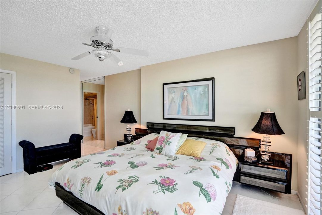Interior space featuring tiled flooring, a ceiling-mounted light fixture with fan, and adjustable window shutters