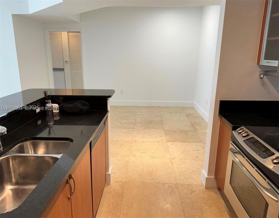 Kitchen featuring stone countertops, flat-panel cabinetry, stainless steel range, double-basin undermount sink, and tile flooring