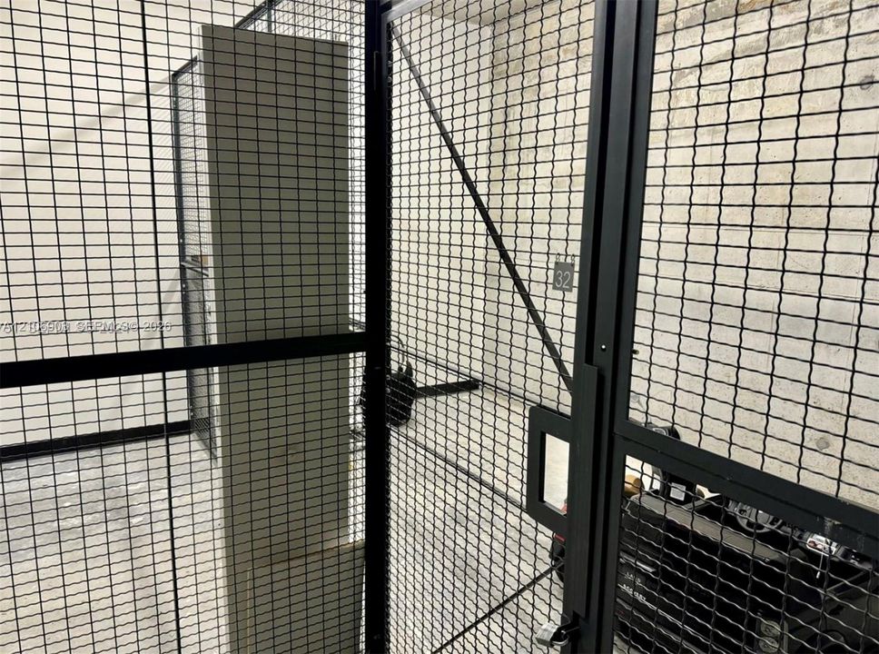 Secured storage unit featuring black wire mesh fencing, a reinforced metal frame, and concrete wall construction