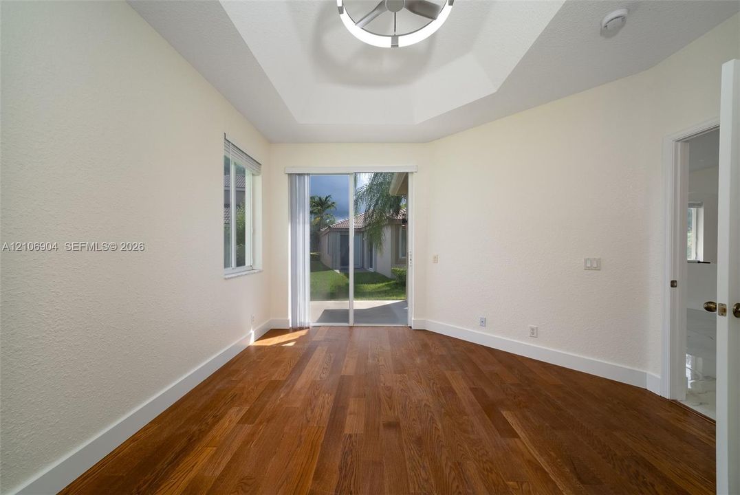 Room featuring wood-finish flooring, tray ceiling with circular LED fixture, and sliding glass door with exterior access