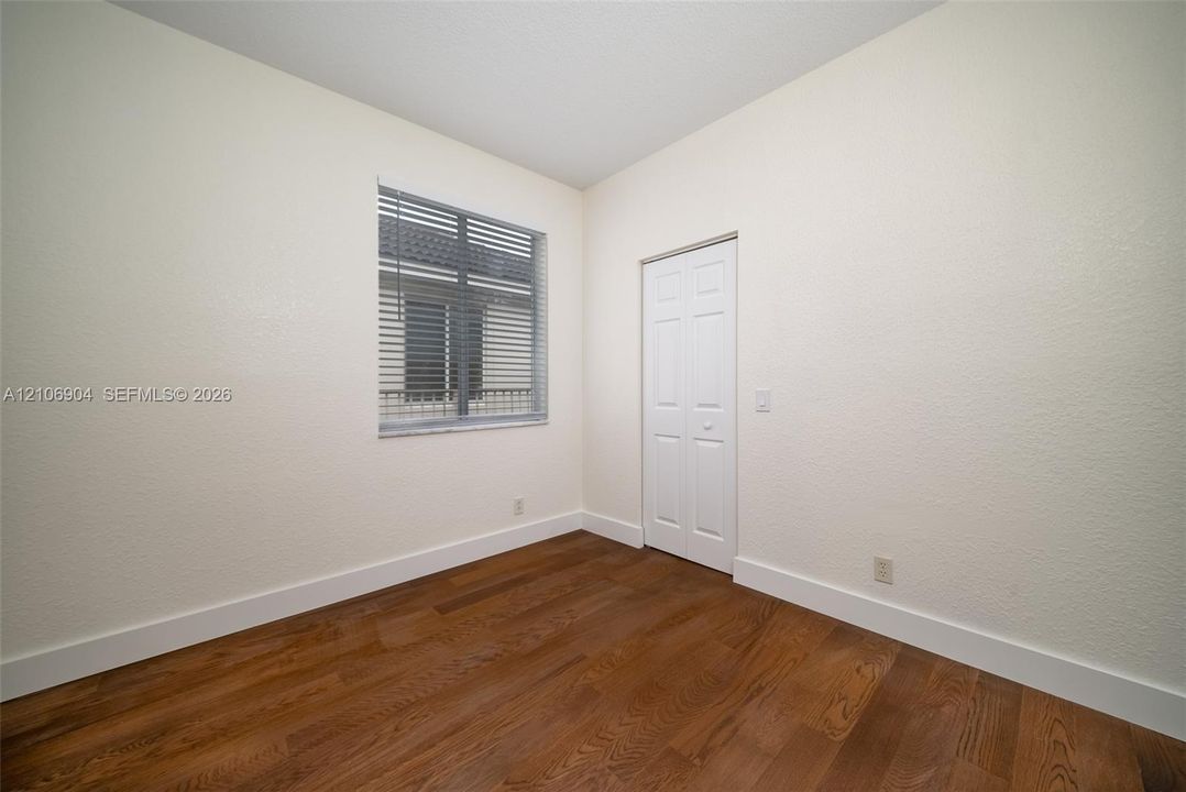 Room featuring wood-finish flooring, a six-panel closet door, and a multi-pane window