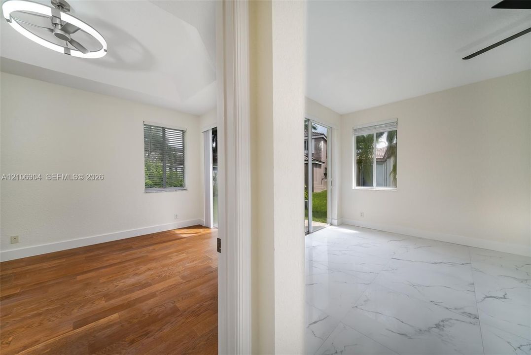 Interior space featuring vaulted ceilings, wood-finish flooring, large-format tile flooring, a contemporary circular LED chandelier, and sliding glass doors