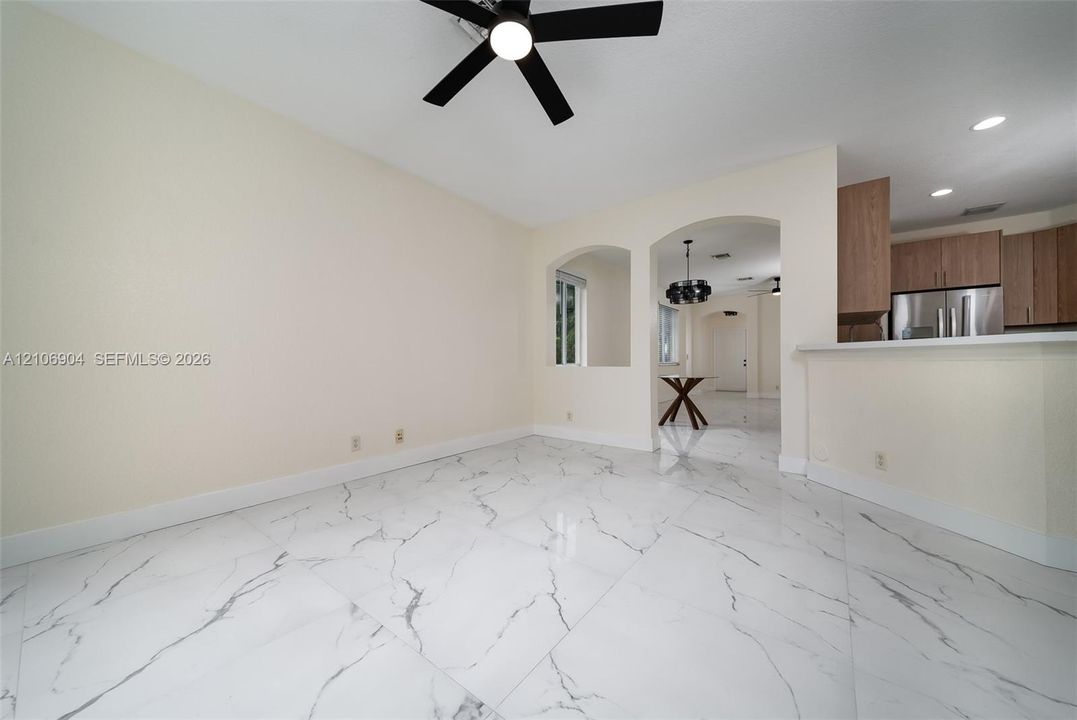 Large-format polished tile flooring featuring a veined pattern, recessed lighting, architectural arched cutouts, and a ceiling-mounted fan with integrated lighting