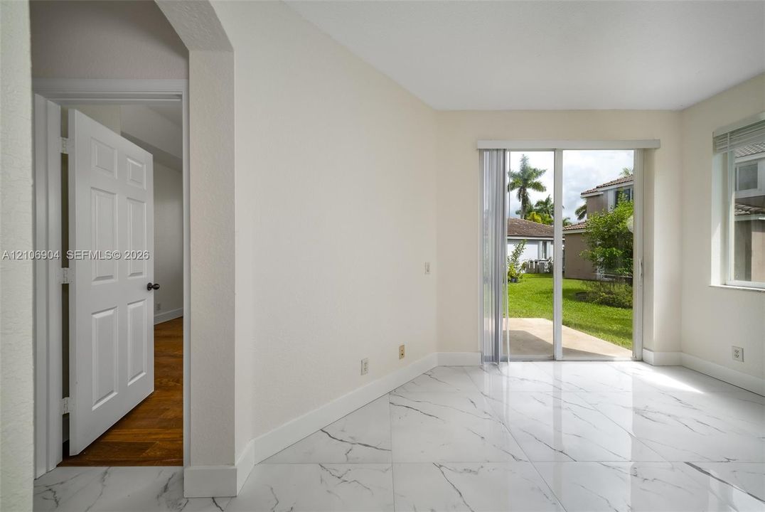 Interior featuring large-format white stone-finish flooring with dark veining, sliding glass patio doors, and a six-panel interior door
