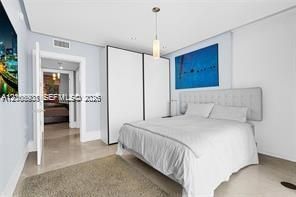 Built-in floor-to-ceiling white cabinetry, smooth-finish stone flooring, recessed ceiling lighting, and a cylindrical pendant light fixture