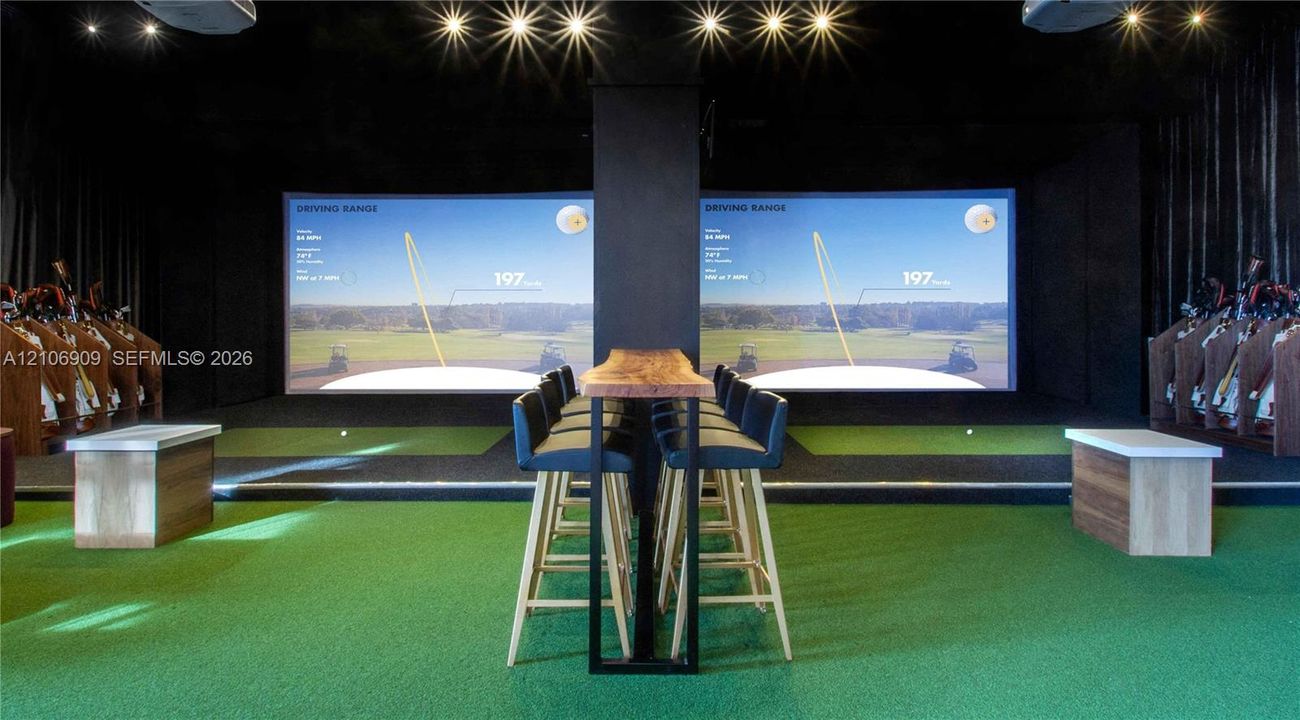 Indoor golf simulator room featuring dual projection screens, high-impact turf flooring, recessed ceiling lighting, and built-in wood cabinetry