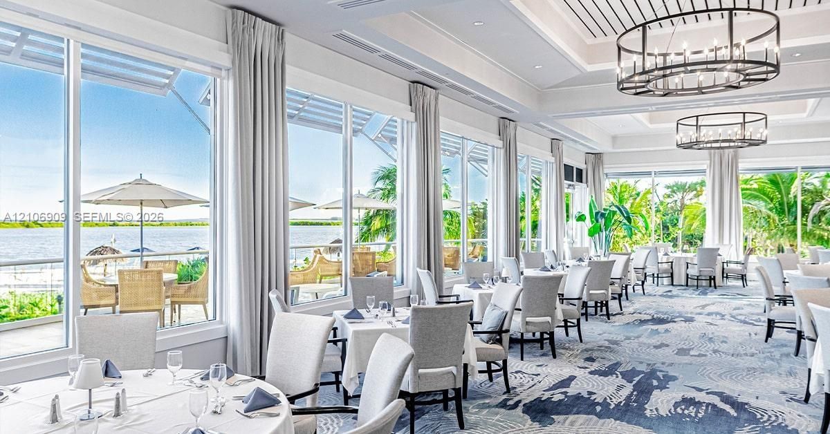 Floor-to-ceiling windows featuring panoramic water scenery, coffered ceilings, and custom oval pendant lighting