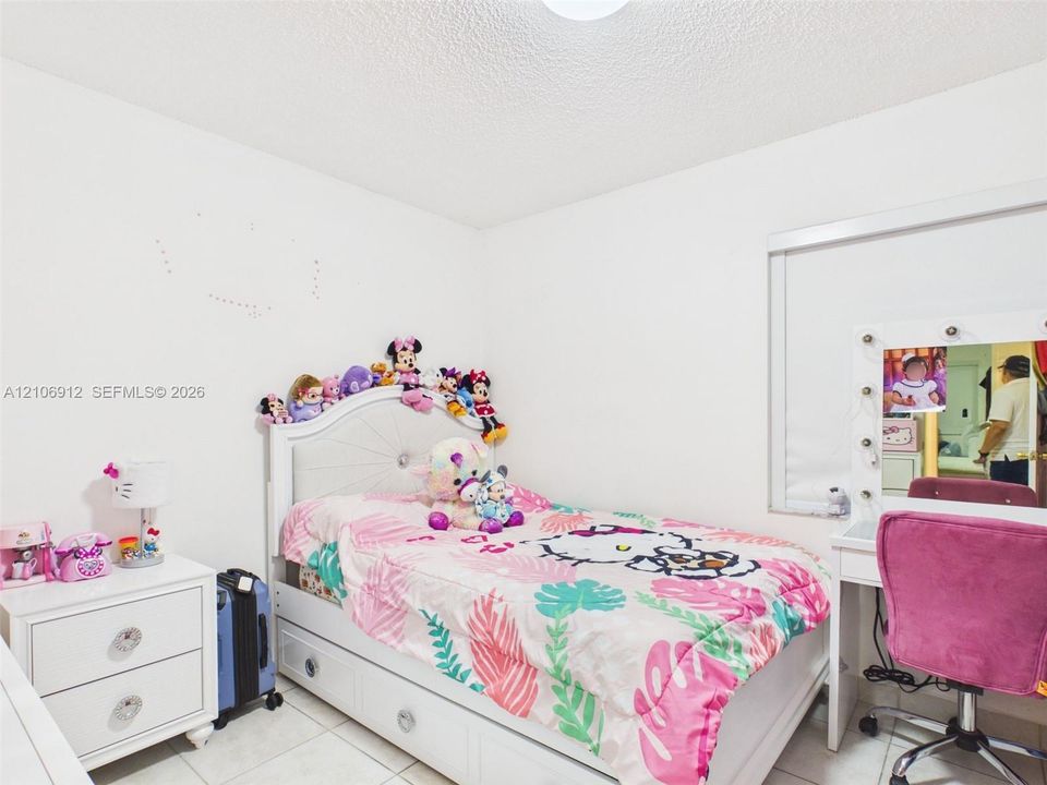 Room featuring white walls, large-format tile flooring, and a window equipped with an integrated roller shade