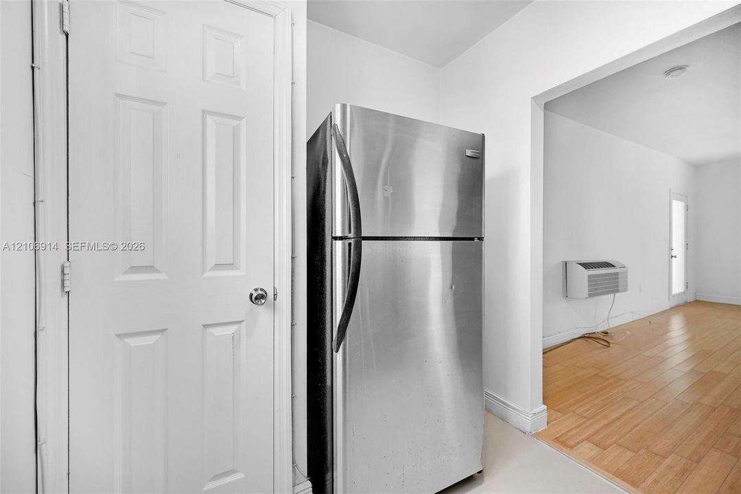Stainless steel refrigerator, wood-finish flooring, and six-panel interior door
