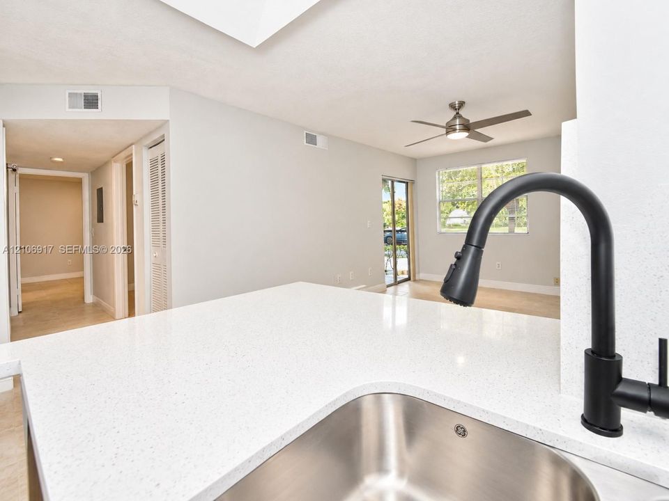 Kitchen island featuring a white stone countertop, undermount stainless steel sink, and matte black gooseneck faucet