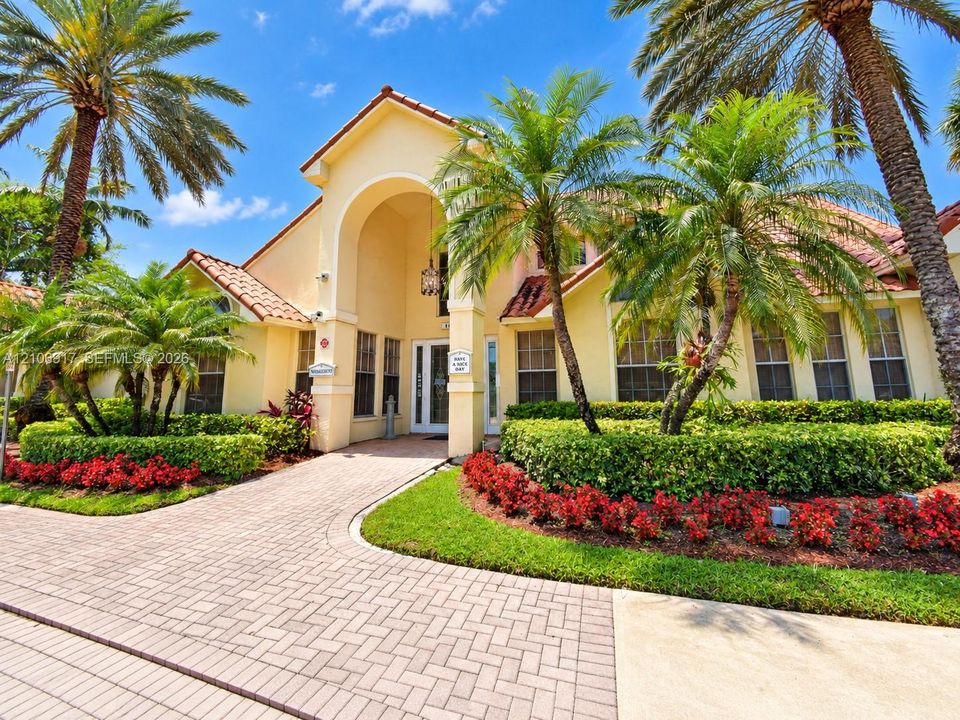 Stucco exterior featuring a tile roof, arched entryway, paved walkway, and mature palm trees