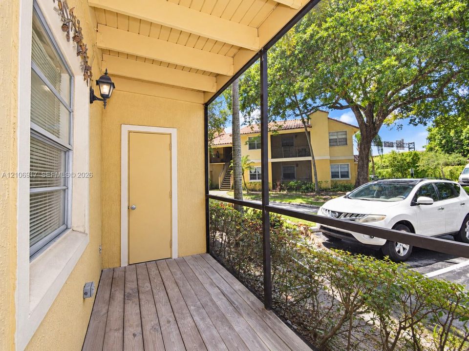Screened porch featuring a wood-plank floor, stucco exterior walls, and wall-mounted exterior lighting