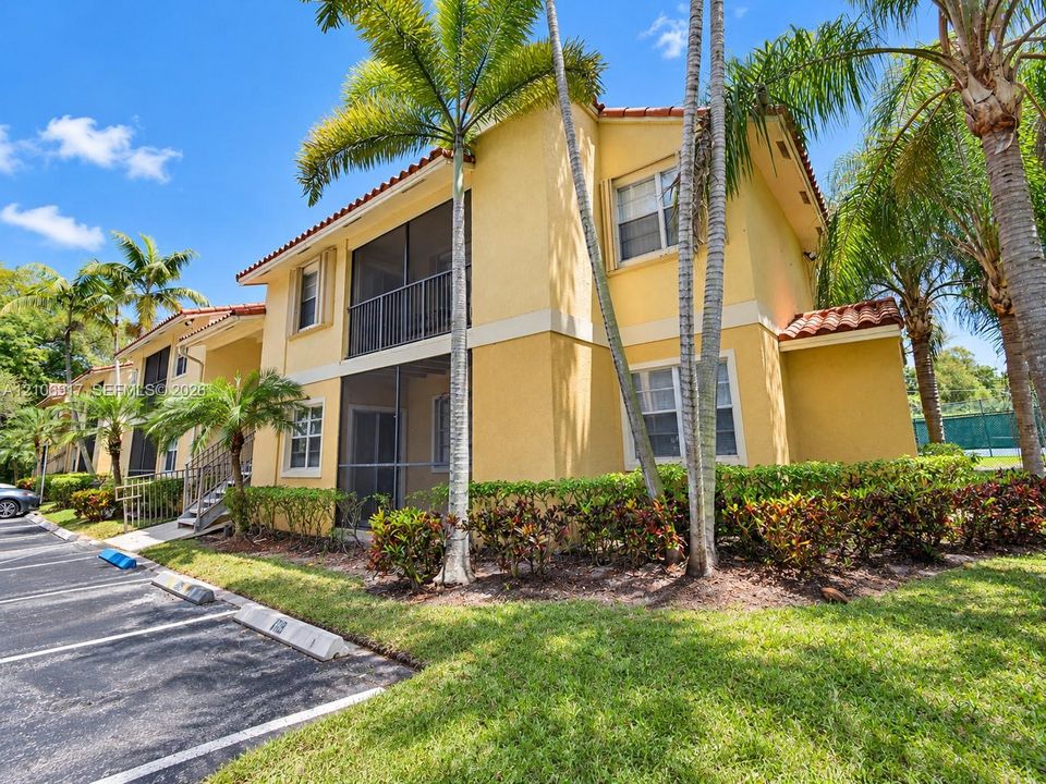 Stucco exterior featuring tile roof accents, screened-in balconies, and mature landscaping