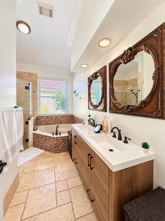 Dual-sink vanity with wood-finish cabinetry, rectangular integrated basins, and stone-tile flooring