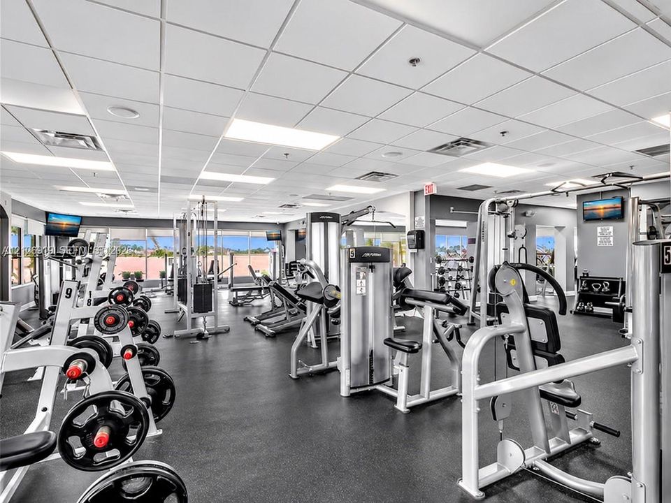 Fitness center featuring rubber flooring, recessed grid ceiling, and a comprehensive collection of built-in strength training equipment