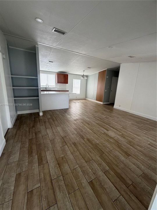 Open-concept interior featuring wood-finish flooring, built-in shelving, kitchen peninsula, recessed lighting, and wooden cabinetry