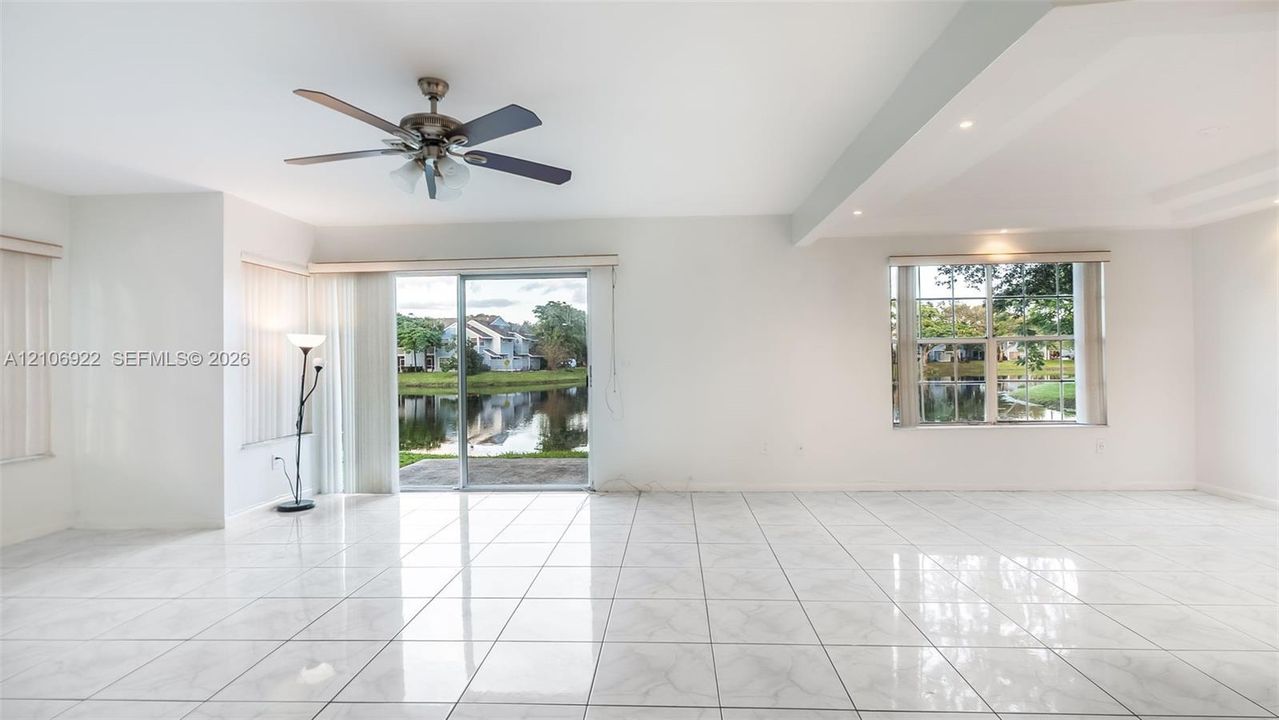 Interior space featuring large-format tile flooring, recessed ceiling lighting, a multi-blade ceiling fan, and sliding glass doors with water scenery