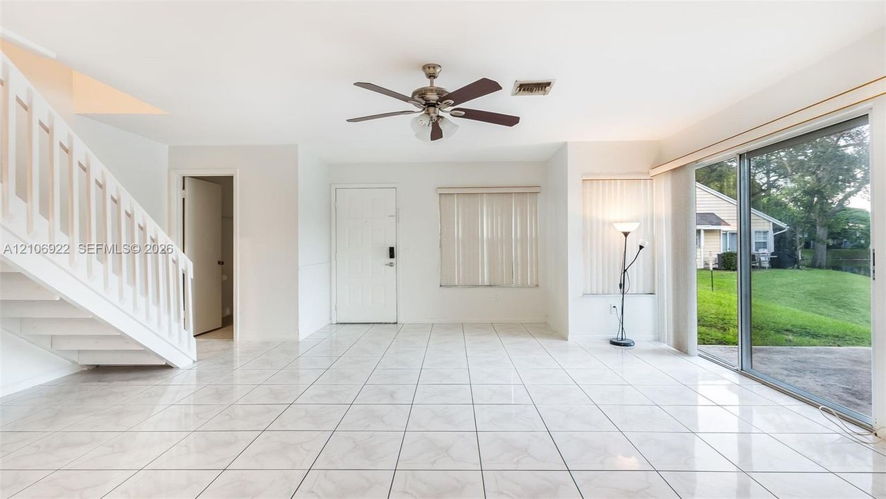 Open floor plan featuring ceramic tile flooring, a staircase with white railing, and sliding glass doors