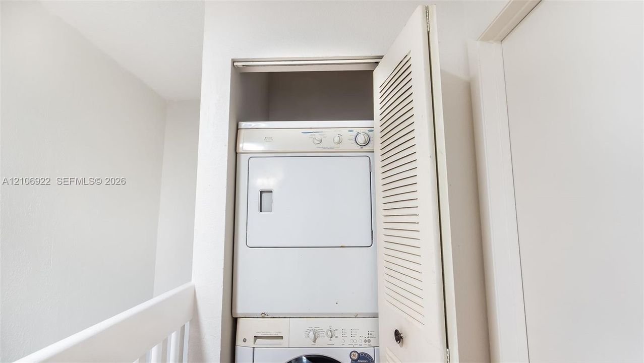 Built-in laundry closet featuring stackable appliances and a louvered bi-fold door
