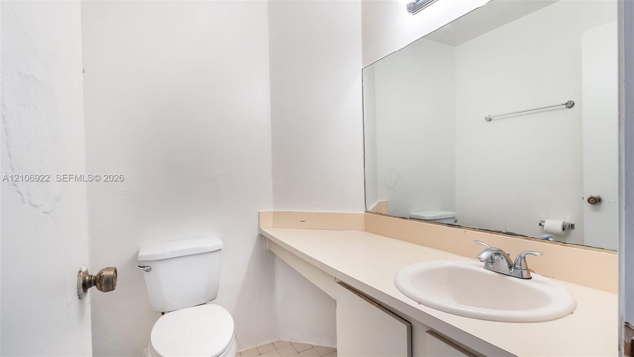 Extended vanity featuring a countertop basin, chrome dual-handle faucet, full-width wall mirror, and toilet