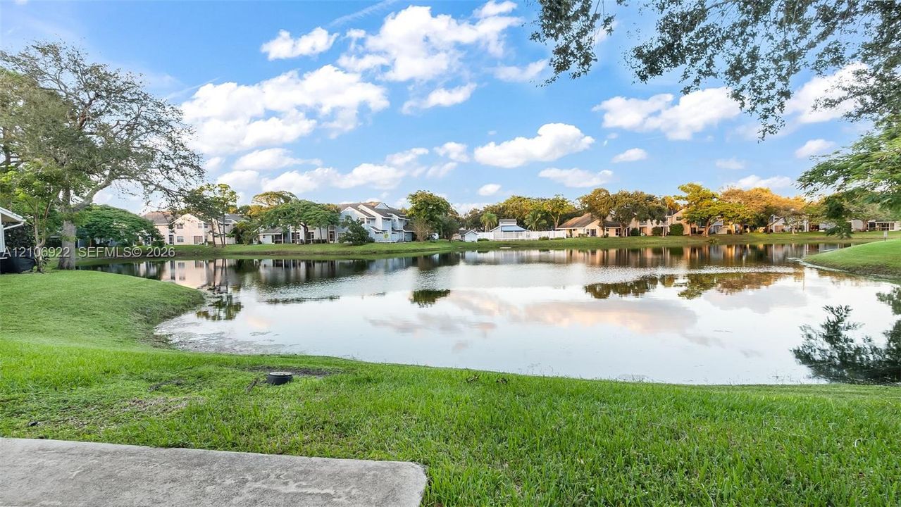 Waterfront grounds featuring a concrete patio, expansive lawn, and mature canopy trees