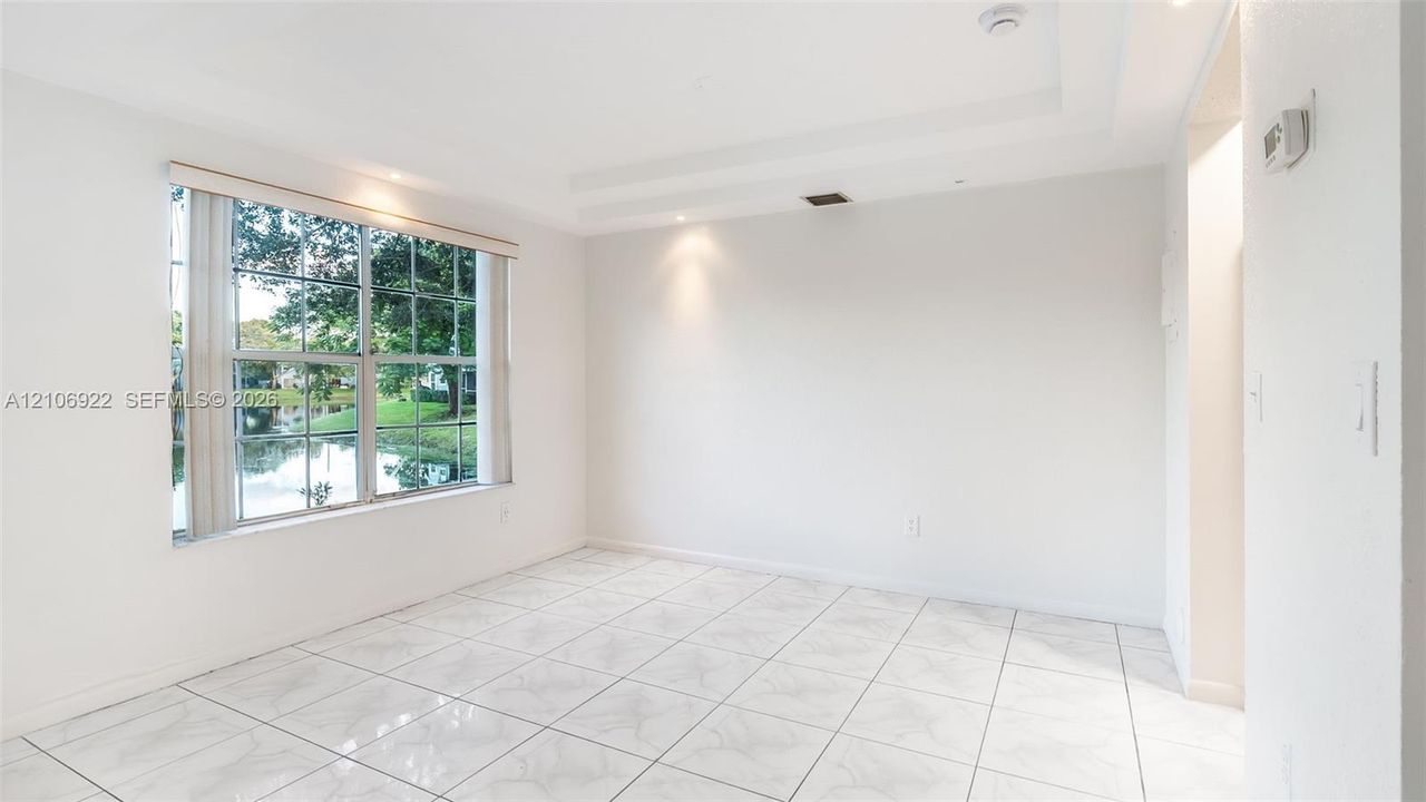Room featuring large grid-pattern windows, polished stone-finish tile flooring, recessed ceiling lighting, and a tiered tray ceiling