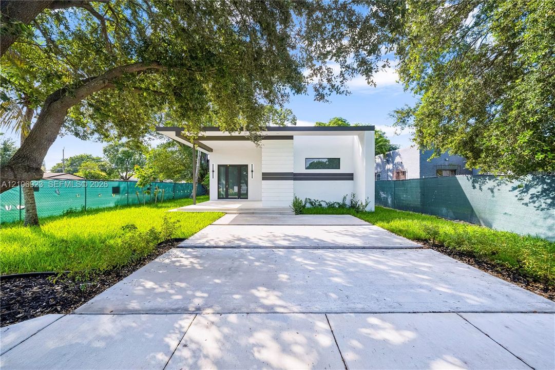 Modern exterior featuring clean lines, a flat roofline, minimalist facade detailing, a paved concrete driveway, and mature landscaping