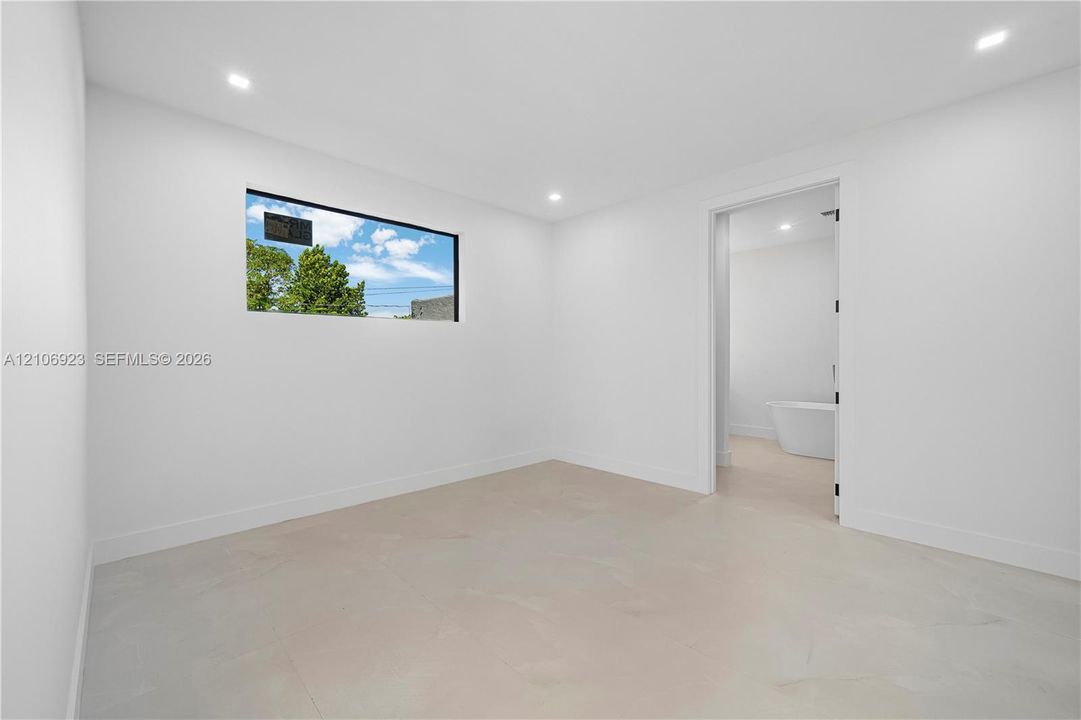 Interior room featuring recessed ceiling lighting, large-format tile flooring, and a horizontal window with a black frame